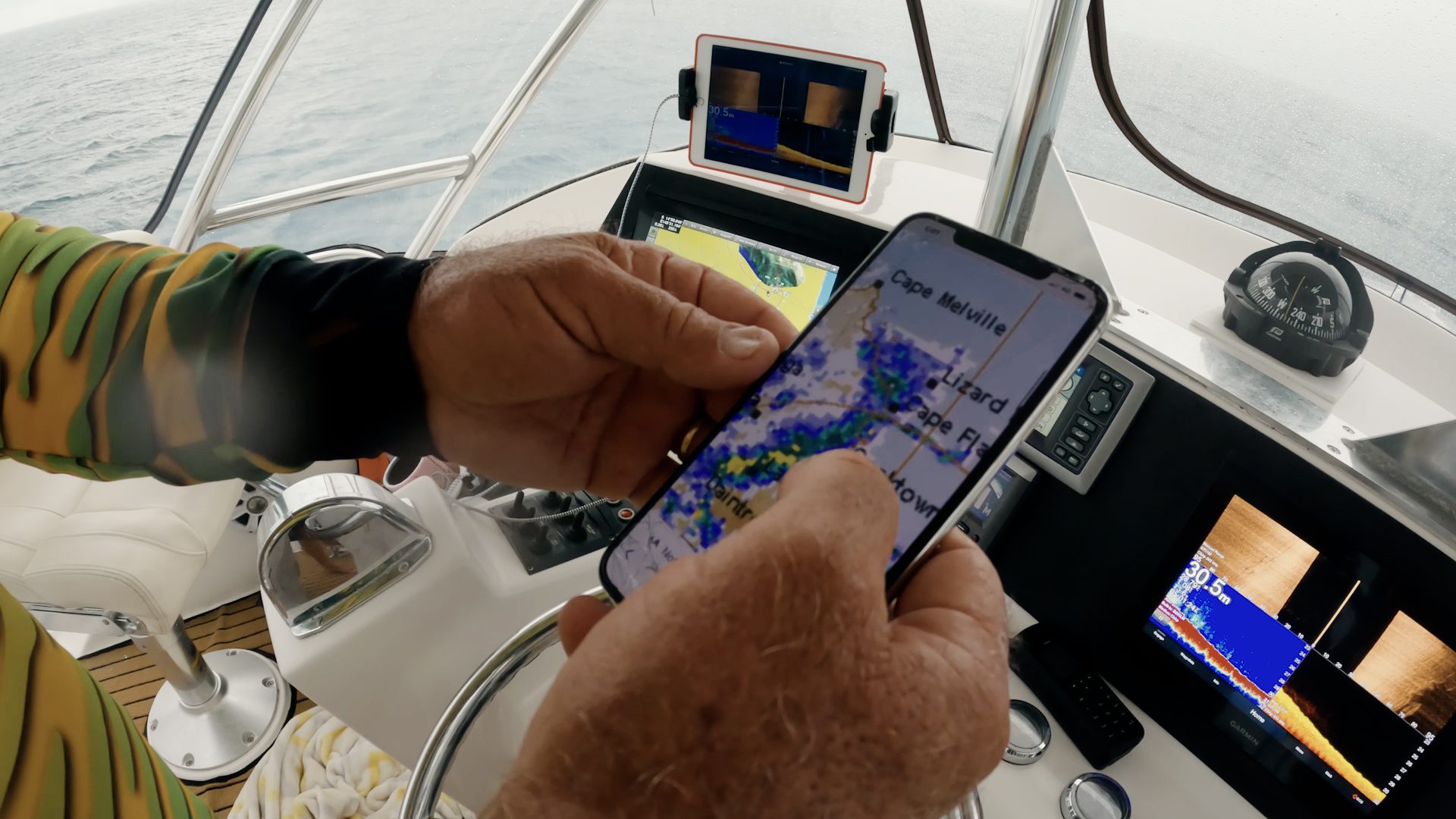 BOM_WeatherForecast_Screenshot Boat skipper looking at weather app in boat